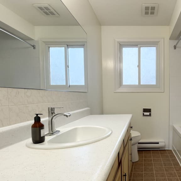 a bathroom with a white sink and brown tiles.