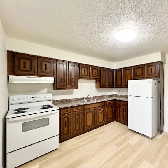 a kitchen with white appliances and wooden cabinets.
