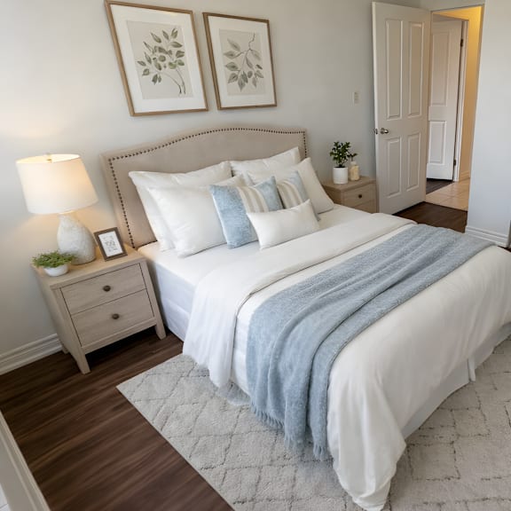 a bedroom with a large bed, a nightstand with a lamp, and two framed pictures on the wall.