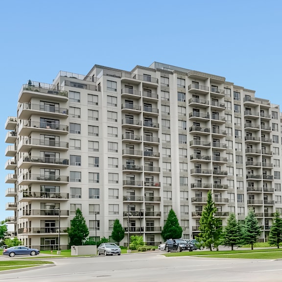 a large apartment building with balconies and trees in front.