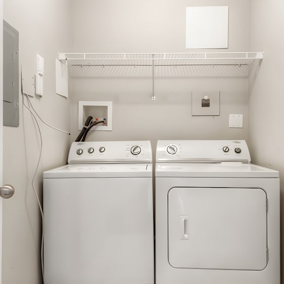 two white washing machines in a small laundry room.