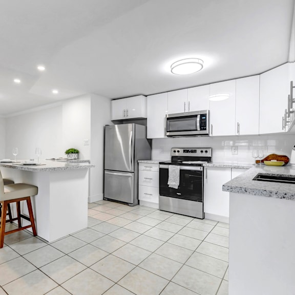 a modern kitchen with a white color scheme and stainless steel appliances.