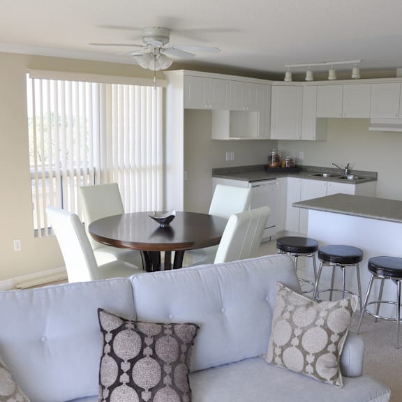 a white couch with a round table and bar stools in a kitchen.