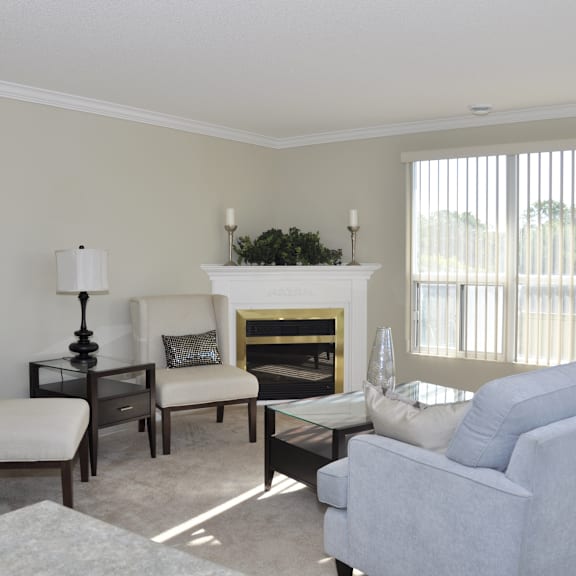 a living room with a fireplace, two chairs, a sofa, and a table.