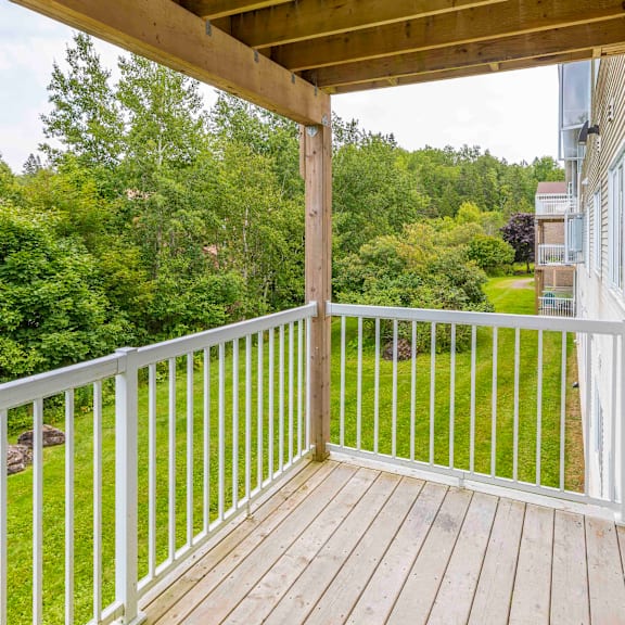 a wooden deck with a white railing overlooks a lush green yard.