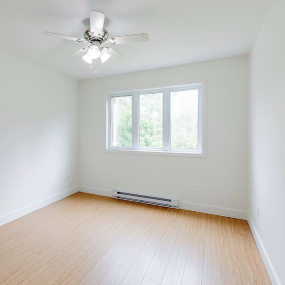 a room with a ceiling fan and a window.