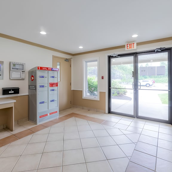 a white tiled lobby with a red exit sign.