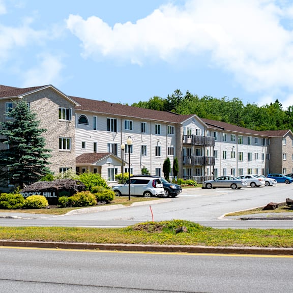 a large apartment complex with a parking lot in front.