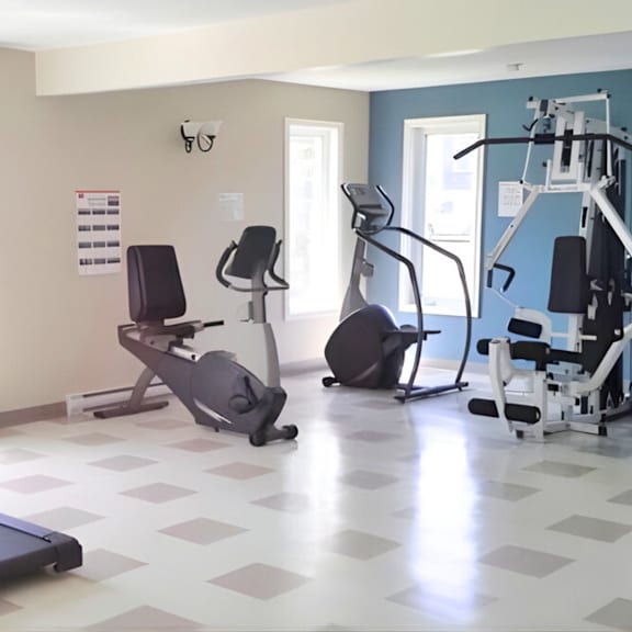 a gym with a variety of equipment including treadmills, stationary bikes, and weight machines.
