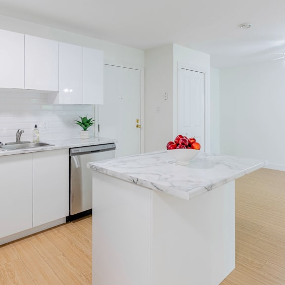 a kitchen with white cabinets and a marble island.