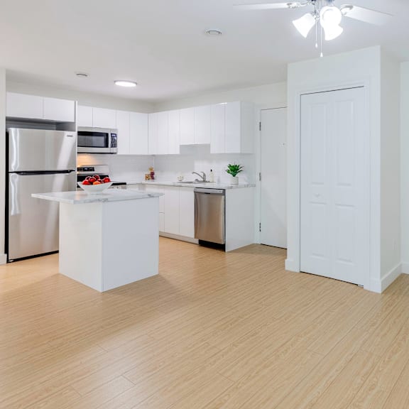 a kitchen with white cabinets and a wooden floor.