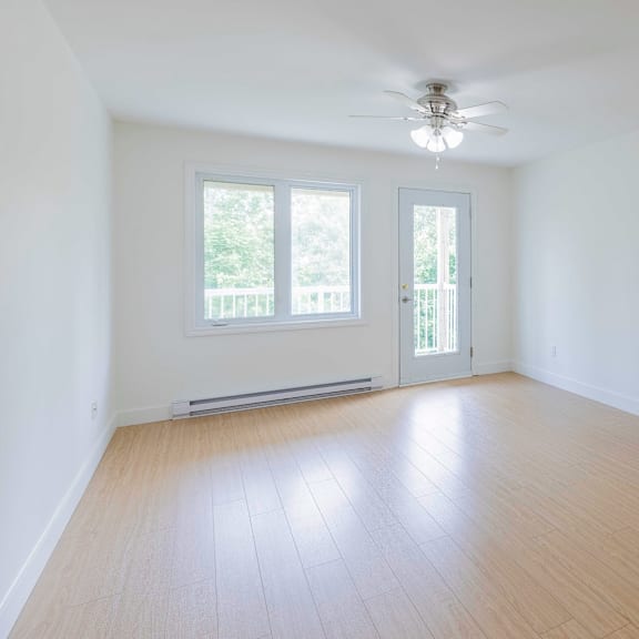 a room with a ceiling fan and a window with a view of trees.