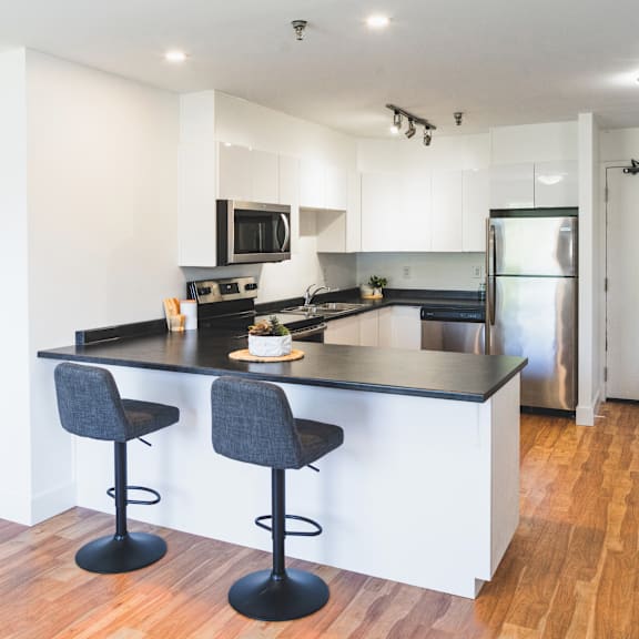 a kitchen with a black countertop and two bar stools.