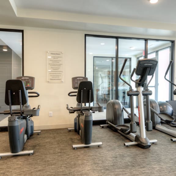 a gym with a variety of exercise equipment including treadmills, stationary bikes, and elliptical machines.