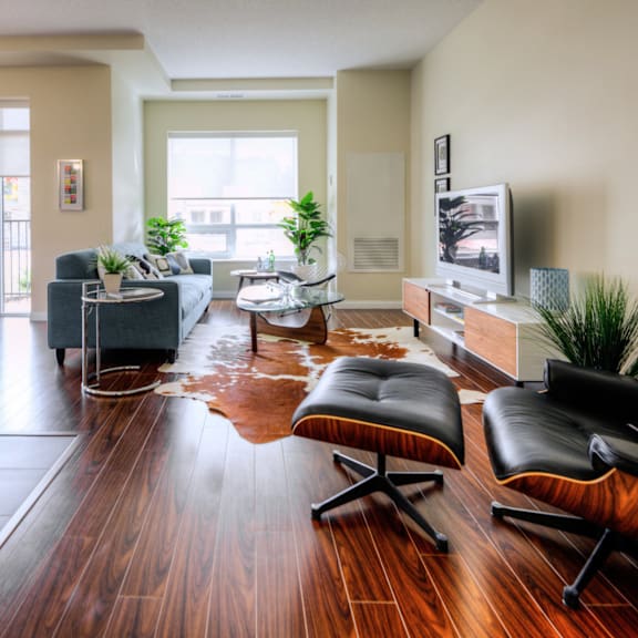 a living room with a black leather chair and a wooden floor.