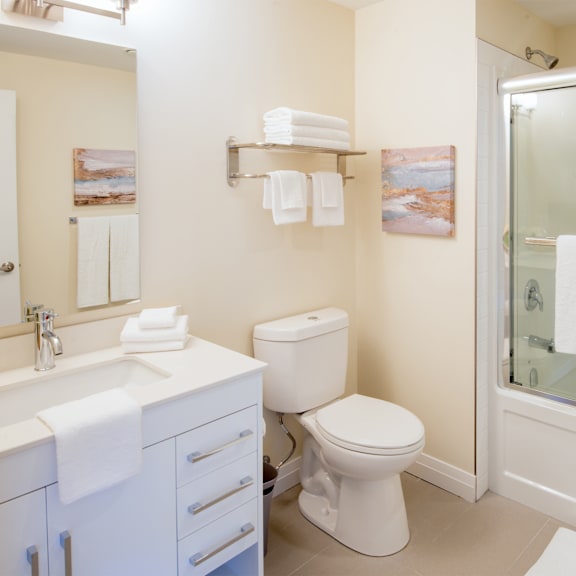 a white toilet sits in a bathroom next to a sink and a shower.