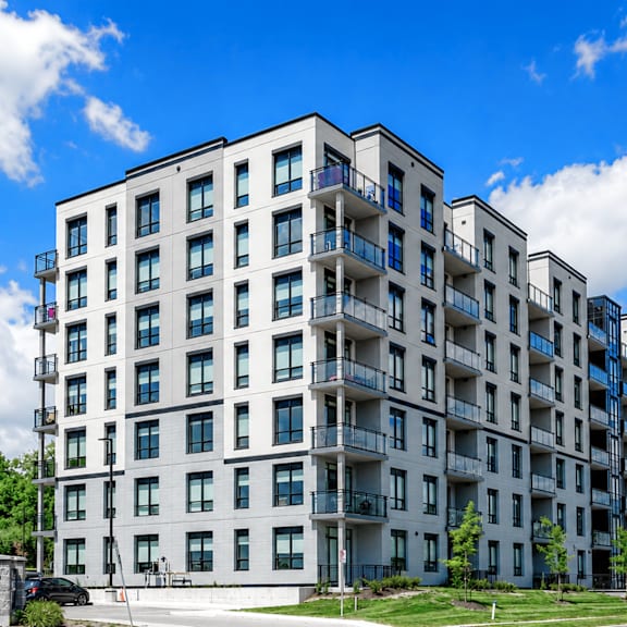 a large white apartment building with balconies and multiple windows.