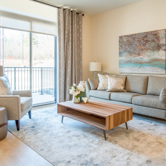 a living room with a grey couch, a wooden coffee table, and a painting on the wall.