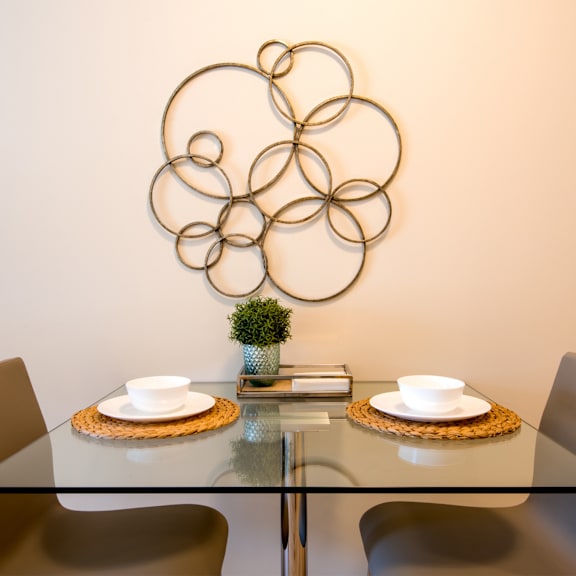 a table with two plates and two chairs with a wall art in the background.
