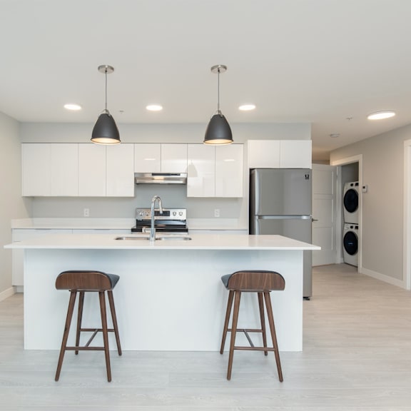 a modern kitchen with white cabinets and a large island with two stools.