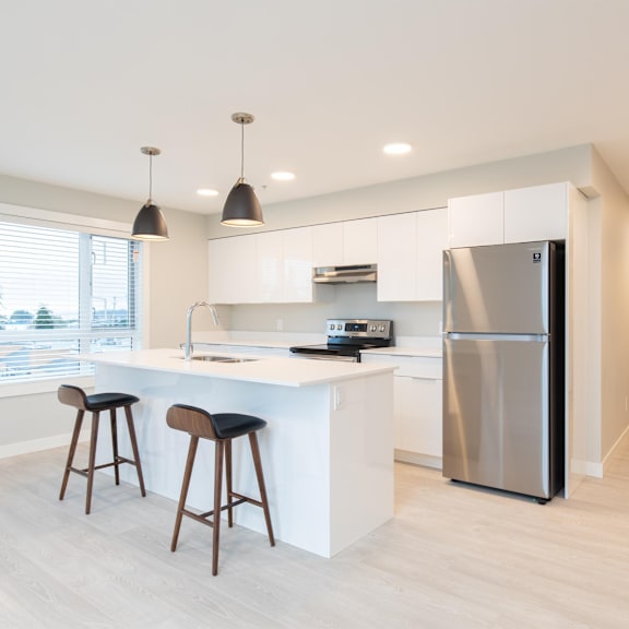 a modern kitchen with a white countertop and a stainless steel refrigerator.