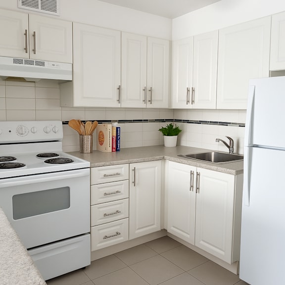 a white kitchen with a stove, sink, and refrigerator.