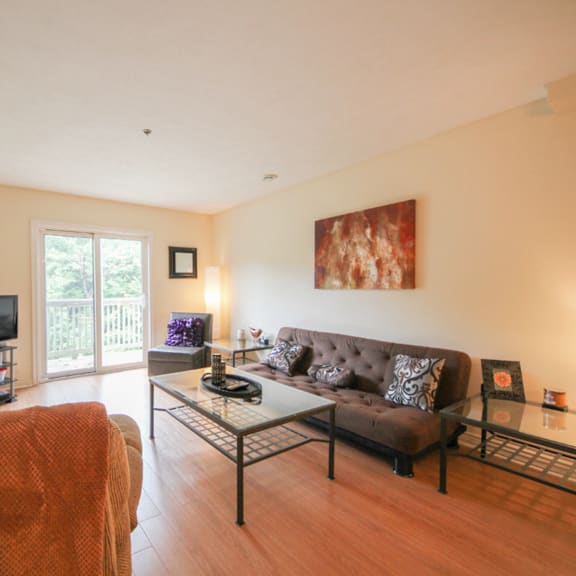 a living room with a brown couch and a glass coffee table.