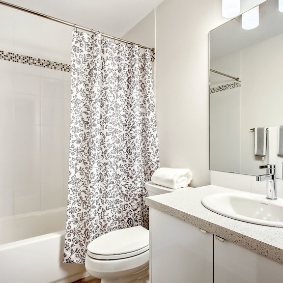 a white bathroom with a sink, toilet, and shower curtain.