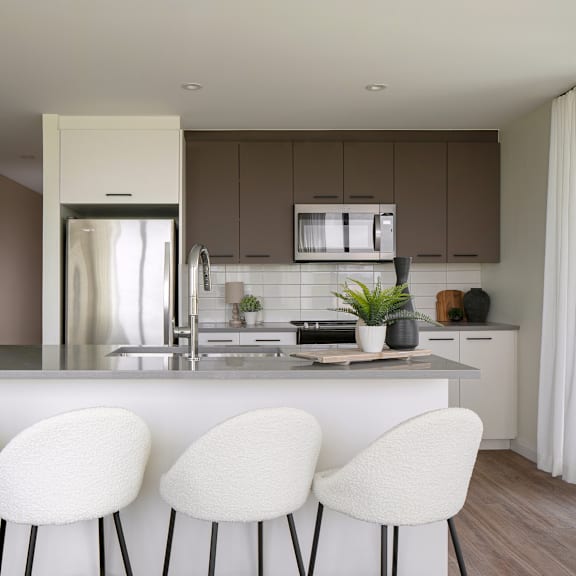 a modern kitchen with white chairs and brown cabinets.