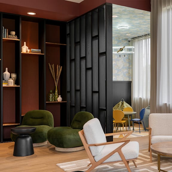 a living room with a green chair, a white chair, and a wooden coffee table.
