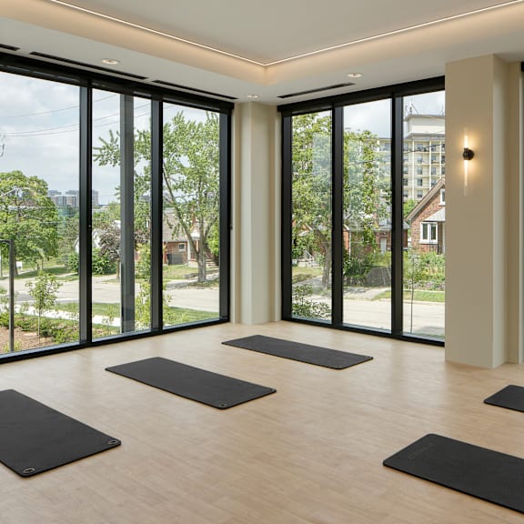 a yoga studio with large windows and yoga mats on the floor.