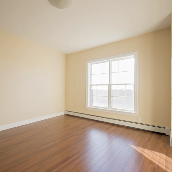 a room with a window and wooden flooring.