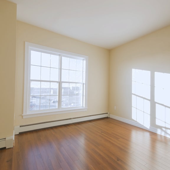 a room with a large window and wooden flooring.