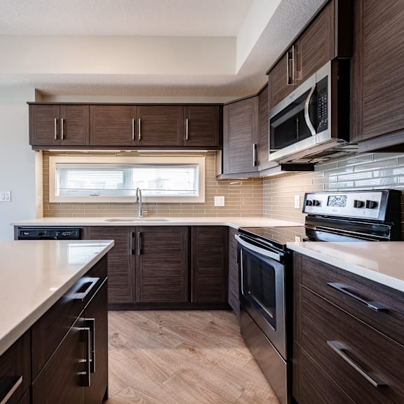 a modern kitchen with dark wood cabinets and stainless steel appliances.