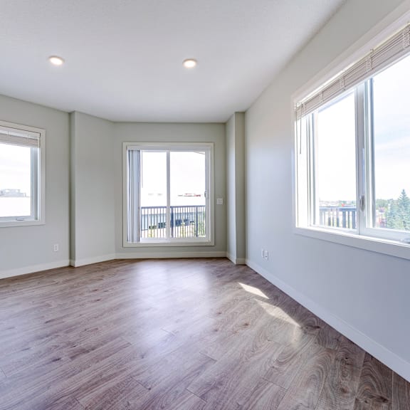 a room with wooden floors and two windows.
