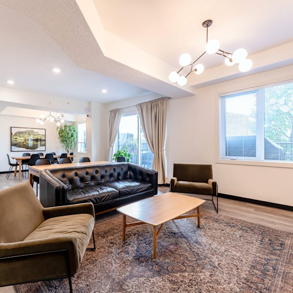 a living room with a black couch, brown armchair, and a wooden coffee table.