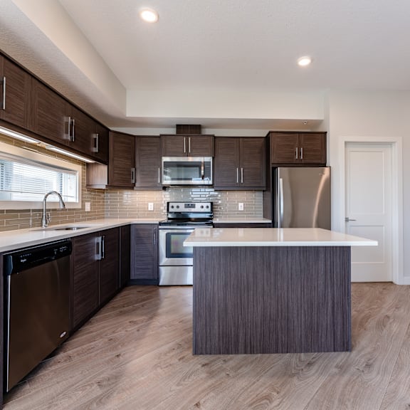a modern kitchen with dark wood cabinets and stainless steel appliances.