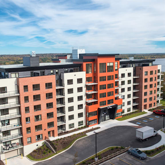 a modern multi-story apartment building with a mix of red and white balconies.