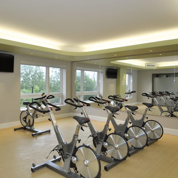 a room with exercise bikes and a television on the wall.