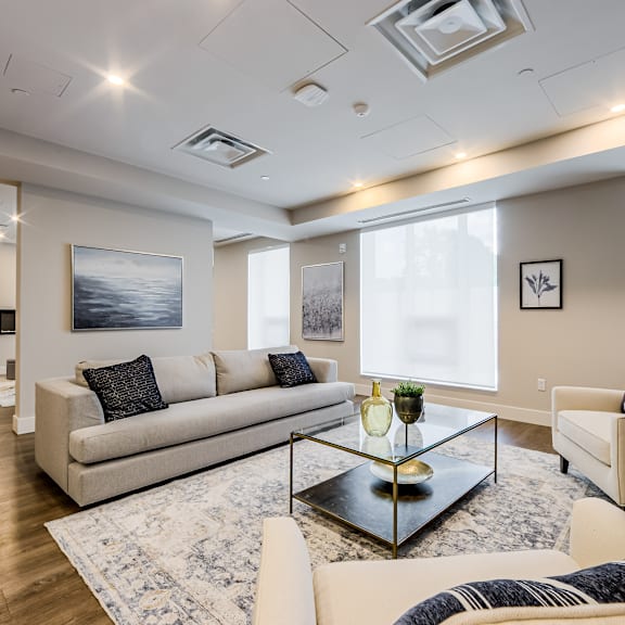 a modern living room with a beige sofa, a glass coffee table, and a large painting on the wall.
