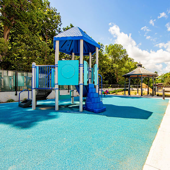 a playground with a blue slide and a gazebo.