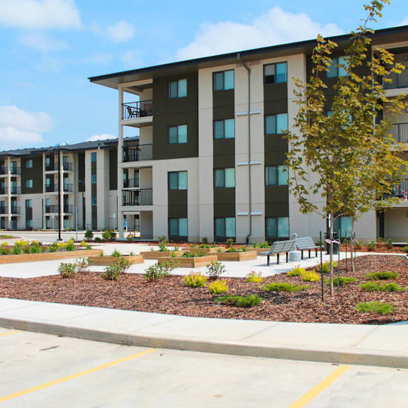a modern apartment complex with a landscaped courtyard in front.