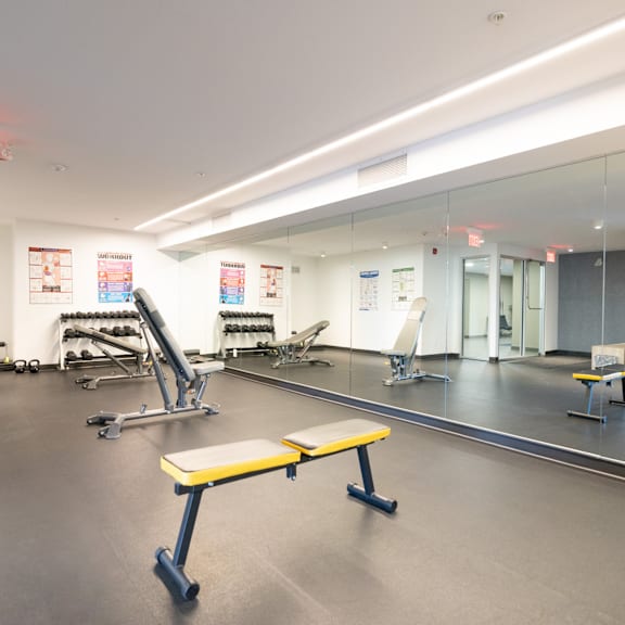 a gym with a variety of equipment including a bench, weights, and a mirror.