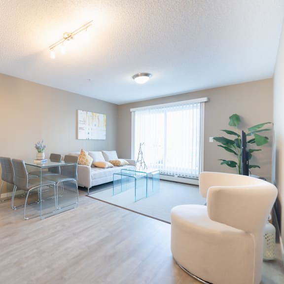 a modern living room with a glass table and white chairs.