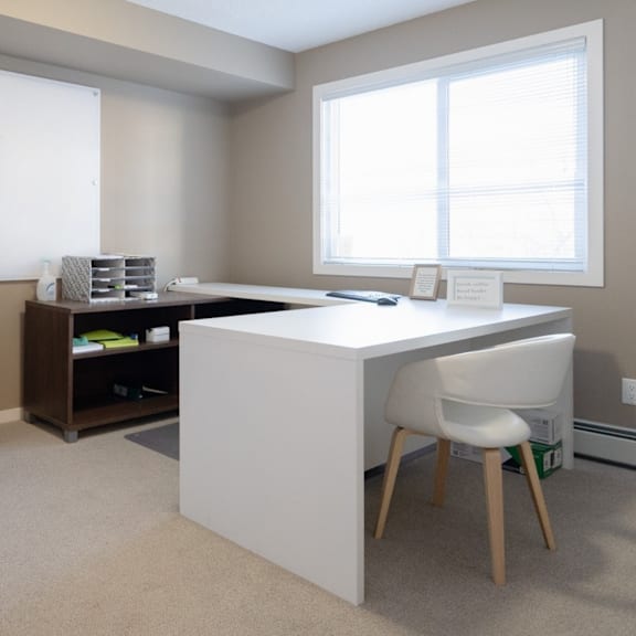 a white desk with a white chair in a room with a window.