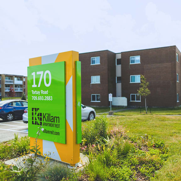 a sign for killam apartment rent in front of a building.