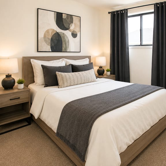 a bedroom with a large bed, a painting on the wall, and two lamps on the nightstand.