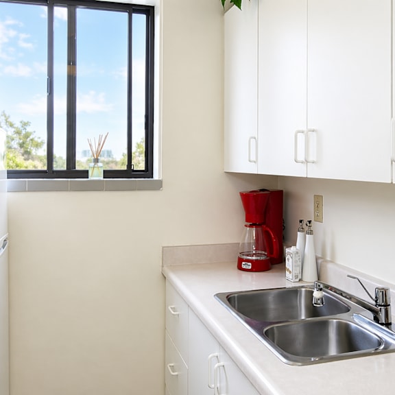a kitchen with a white fridge, white cabinets, and a window.