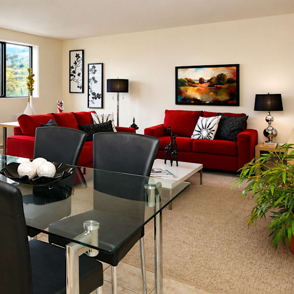 a modern living room with a glass dining table and red couch.