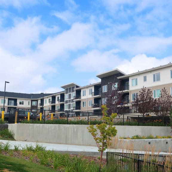 a row of modern townhouses with a concrete wall and greenery in the foreground.